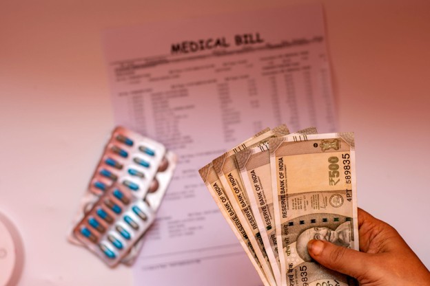 A patient holding money beside medicine and a medical bill